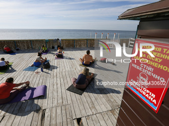 Ukrainians perform yoga marking the International Day of Yoga near a warning sign of mine danger on the beach, amid Russia's invasion of Ukr...