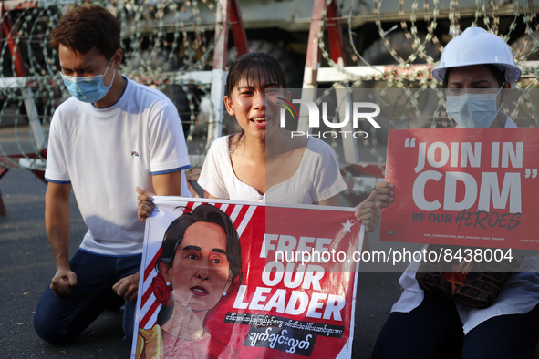A protester cries in front of armoured vehicles as she holds a banner with a picture of Aung San Suu Kyi during a demonstration against the...
