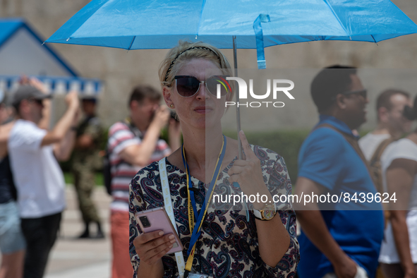 A woman uses an ombrella for protection during a heatwave in Athens, Greece, on June 23, 2022 