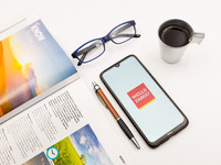In this photo illustration a Wells Fargo logo seen displayed on a smartphone screen on a desk next to a cafe, a pen, glasses and a magazine...