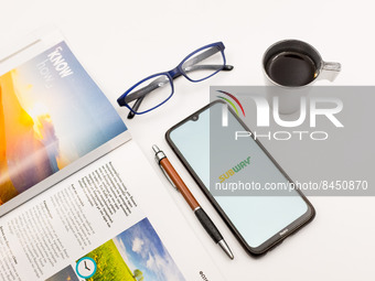 In this photo illustration a Subway logo seen displayed on a smartphone screen on a desk next to a cafe, a pen, glasses and a magazine in At...