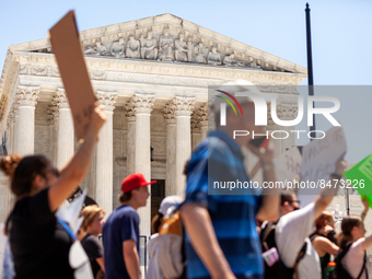 Pro-choice demonstrators march in front of the Supreme Court and the statement on its facade, 