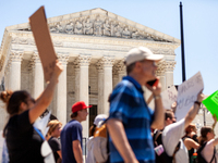 Pro-choice demonstrators march in front of the Supreme Court and the statement on its facade, 