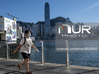 A women wearing a face mask walking pass the Hong Kong Skyline on July 12, 2022 in Hong Kong, China. The Hong Kong Government announce that...