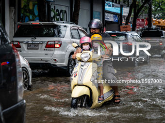 A family on a motorcycle makes their way through heavy traffic on a flooded street in Bangkok on July 21, 2022. (