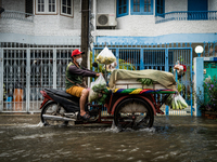 A fresh vegetable push cart vendor drives his motorcycle through heavy flooding in Bangkok on July 21, 2022. (