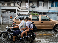 Teenage boys commute to school on a motorcycle during heavy flooding in Bangkok on July 21, 2022. (