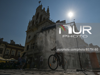 A cyclist rides under a water sprinkler placed on the Market Square in Rzeszow. 
On Saturday, July 23, 2022, in Market Square, Rzeszow, Podk...
