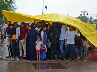 People take shelter under a plastic sheet during monsoon rain, near Jal Mahal in Jaipur, Rajasthan, India, Sunday, July 24, 2022.(