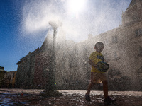 A boy is cooling by a water sprinkler at the Small Square in Krakow, Poland on July 25, 2022. Hot air masses from over Africa covered most o...