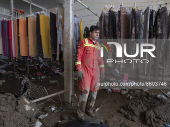 An Iranian firefighter stands at a damaged shop which is covered with mud after flash flooding in the flooded village of Imamzadeh Davood in...