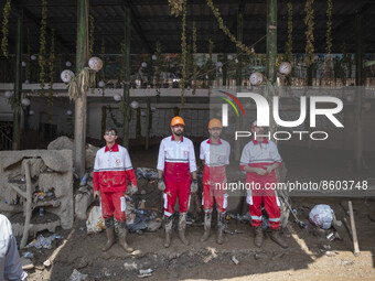 Members of the Iranian Red Crescent Society (IRCC) look on while standing in front of a restaurant which is damaged and covered with mud in...