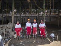 Members of the Iranian Red Crescent Society (IRCC) look on while standing in front of a restaurant which is damaged and covered with mud in...