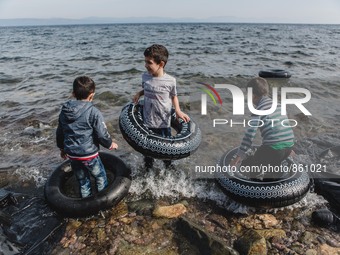 Children play in the waves with rubber rings purchased in case of emergency on the sea, in Lesbos, on September 26, 2015.  (