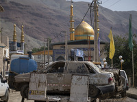 A destroyed car which is covered with mud carrying by a truck near a mosque Five days after a sudden flooding in the flooded village of Mazd...