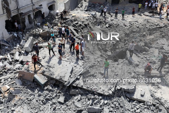 Palestinians inspect the ruins of a collapsed building destroyed by an Israeli air strike in Gaza City, on August 6, 2022. - Israel on Augus...