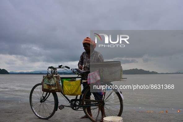 Fish vendor arrives to clean his fish container in the banks Brahmaputra river during a cloudy day, in Guwahati ,India on August 6,2022. 