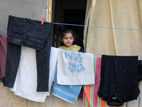 A Palestinian girls watch on August 8, 2022 from her balcony as residents assess the damage in areas hit by Israeli air strike over the past...
