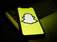 Snapchat logo displayed on a phone screen and a laptop keyboard are seen in this illustration photo taken in Krakow, Poland on August 10, 20...