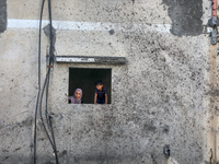 Palestinians look out of a damaged building in Gaza City, on August 12, 2022.- An Egypt-brokered ceasefire reached late on August 7 ended th...