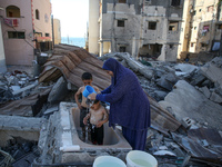 A Palestinian woman washes her children at her destroyed house in Gaza City, on August 12, 2022.- An Egypt-brokered ceasefire reached late o...