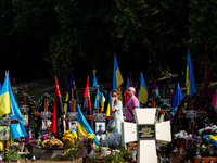People visit the graves of fallen soldiers, killed by the Russian army during the 2022 invasion in the old town of Lviv on Lychakiv Cemetery...