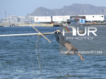 A migrant pictured jumping into sea in Kos harbour, as awaiting to be processed by the Greek police and given paperwork entitling them to le...