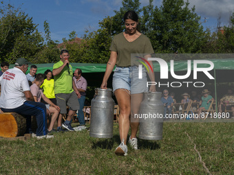 A young woman participates in the race of pots, used to transport milk, they are filled with water with a weight of 45 kilograms each and th...