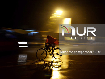 An indian cyclist passes through a wet road during rains,in Allahabad on October 28,2015. (