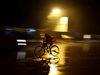An indian cyclist passes through a wet road during rains,in Allahabad on October 28,2015. (