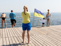 Tourists take a photo by Ukrainian flag by the boulevard  in a famous Black Sea resort in  Odessa, Ukraine as the country surpasses 6 months...