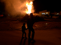 A boy and his father walk in front of a bonfire in northwestern Crete as Easter celebrations begin by burning an effigy of Judas. (