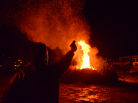A man shoots a pistol in northwestern Crete as Easter celebrations begin by burning an effigy of Judas. (