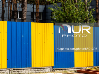 Blue and yellow fence is seen in the Irpin, Ukraine on Septembre 8, 2022. Ukrainian national flag colours - blue and yellow - have a strong...
