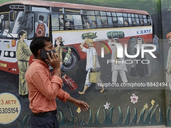 A man talks on a phone, walks past a wall graffiti near a famous Kempegowda bus station in Bangalore, India, 13 September, 2022.  (