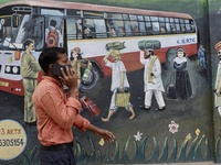 A man talks on a phone, walks past a wall graffiti near a famous Kempegowda bus station in Bangalore, India, 13 September, 2022.  (