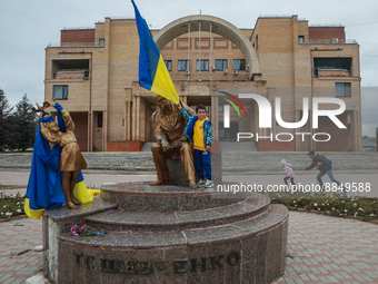 A boy holds the Ukrainian flag attached to the monument to the poet Taras Shevchenko in the city center of liberated Balakliya, Kharkiv regi...