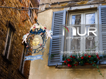 Artful guild sign of the hotel Albergo del Sole, next to an open window with shutters in a historic center of Citta Alta (Upper Town) in Ber...