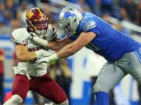 Linebacker Cole Holcomb (55) of the Washington Commanders  holds the line against offensive tackle Dan Skipper (70) of the Detroit Lions dur...