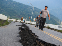People walk on a damaged road with fissures after a magnitude 6.8 earthquake hitting Taiwan caused severe damages to buildings, bridges and...