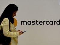 A woman with a mobile phone walks past a MasterCard logo in Global Fintech Fest event in Mumbai, India, 20 September, 2022.  (