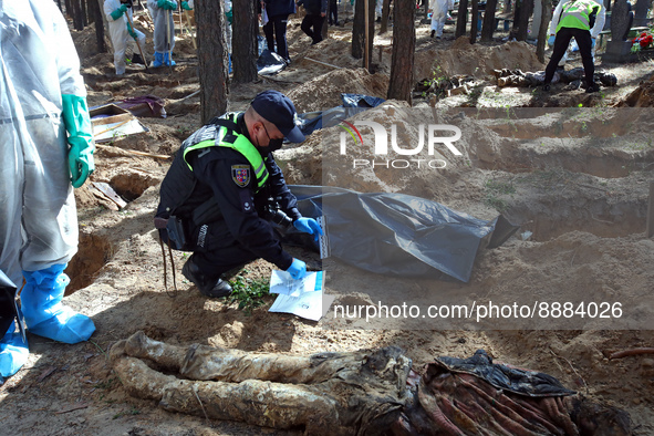 IZIUM, UKRAINE - SEPTEMBER 19, 2022 - A police investigator is seen at work during the exhumation of the bodies of Izium residents tortured...