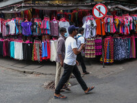People walk past clothing shops at a market in Colombo on September 20, 2022. (