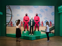 LONDON, UNITED KINGDOM - SEPTEMBER 21, 2022: Staff members look at the iconic pink guard costumes and green tracksuit from hit Netflix serie...