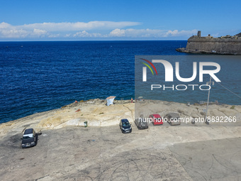 Cars parked on rocky Mediterranean Sea coast are seen in Valletta, Malta on 21 September 2022  (