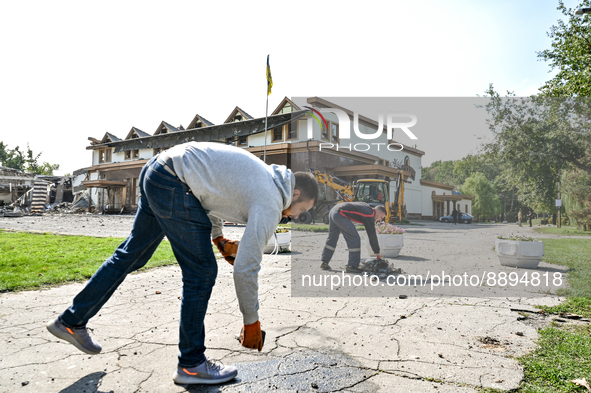 ZAPORIZHZHIA, UKRAINE - SEPTEMBER 22, 2022 - Men clean up the territory outside the restaurant and hotel after a russian S-300 missile hit,...