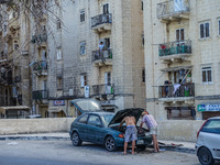 Men trying to repair their old car in the street in the residential area are seen in Valletta, Malta on 21 September 2022  (