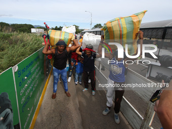 People carrying packages are seen crossing through the Simon Bolivar International Bridge, during the official reopening ceremony of the bor...