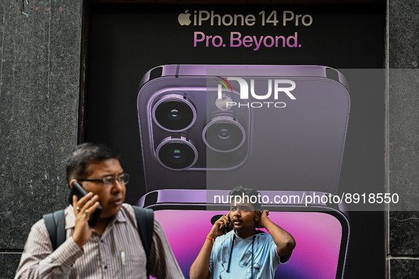 Men talk on their mobile phones in front of an iphone 14 advertisement, in Kolkata on September 27, 2022. Apple Inc. said on Monday it will...