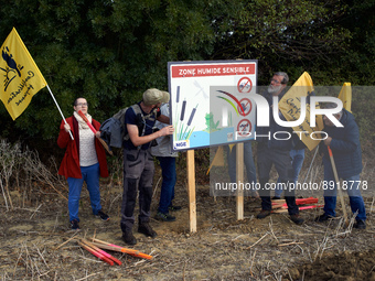 Opponents look at a NGE's placard near an excavation in a field reading 'Sensitive wetlands'. The collective 'La Voie Est Libre' (ie 'The Wa...
